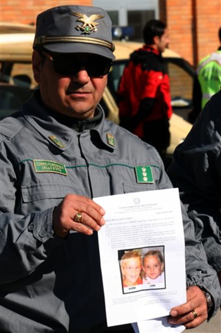 A forestry police officer holds up a sheet showing the pictures of two missing 6-year old twin girls who disappeared after their father died in an apparent suicide, in Cerignola, near Bari, Italy, on Feb. 3.